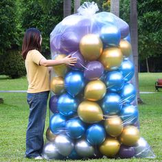 a person standing next to a large pile of balloons