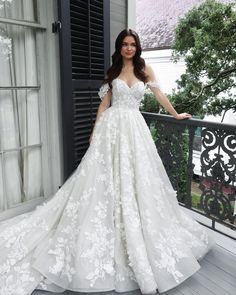 a woman in a white wedding dress standing on a porch with her hands on her hips