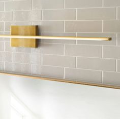 a gold towel rack on the wall above a toilet paper dispenser in a bathroom