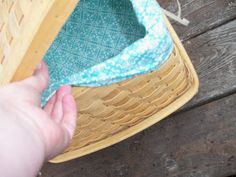 a person is holding a blue towel in a wicker basket on a picnic table