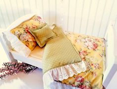 a bed with pillows on top of it next to a flowery pillow case and pink flowers