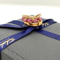 a gold ring with pink and white stones sitting on top of a blue ribbon