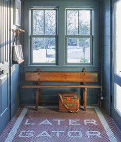 a wooden bench sitting in front of a window next to a bag on the floor