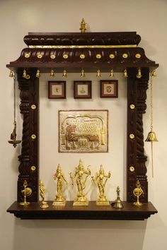 an ornate wooden shelf with gold decorations and pictures on the wall in front of it