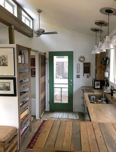 an open kitchen and living room with wood flooring on the walls, overhead lighting