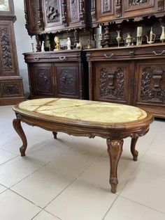 an antique coffee table with marble top in a room filled with wooden cabinets and drawers