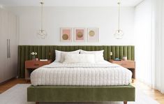 a bed with green headboard and foot board in a white walled bedroom, along with two paintings on the wall