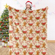 a woman holding up a christmas themed blanket with gingerbreads and candy canes on it