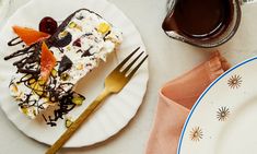 a piece of cake sitting on top of a white plate next to a cup of coffee