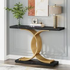 a console table with a black marble top and gold metal base in a living room