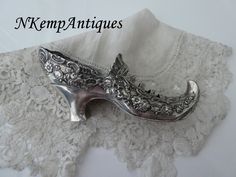 a pair of silver shoes sitting on top of a white lace covered tablecloth with the words kremp antiques