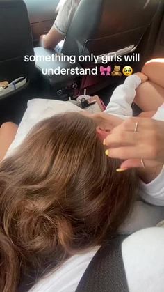 a woman laying in the back of a car with her hand on top of another person's head