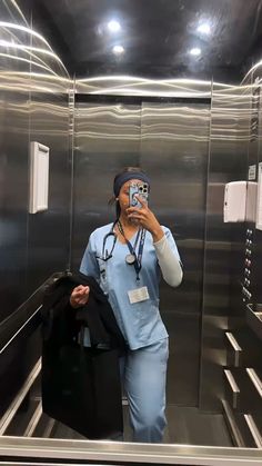 a woman in scrubs taking a selfie with her cell phone while standing on an escalator