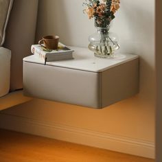 a glass vase with flowers on top of a table next to a book and cup