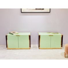 two green sideboards sitting next to each other in front of a painting on the wall