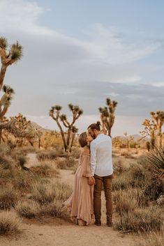 a couple kissing in the desert surrounded by cacti