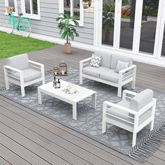 an outdoor living room with white furniture on a rug in front of a patio area