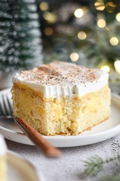 a piece of cake sitting on top of a white plate next to a christmas tree