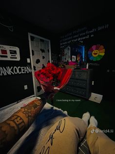 a man laying in bed with flowers and tattoos on his arm, holding a bouquet of red roses