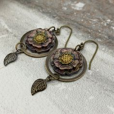 "Sometimes you want to celebrate spring without going pastel. These boho casual earrings mix floral with understated style. The flowers are hand-painted polymer clay; and the leaf charms, findings and ear wires are antique brass.  Length: 2\" from the top of the ear wire Width: approximately 3/4\"" Bohemian Brass Flower Earrings, Nickel-free Bohemian Flower Earrings, Bohemian Flower Earrings As Gift, Bohemian Floral Print Flower Earrings As Gift, Bohemian Polymer Clay Nickel-free Earrings, Bohemian Nickel-free Polymer Clay Earrings, Bohemian Polymer Clay Flower Drop Earrings, Bohemian Flower Drop Earrings In Polymer Clay, Bohemian Drop Earrings With Handmade Flowers