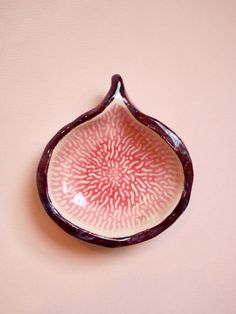 a pink and white bowl sitting on top of a table next to a brown wall