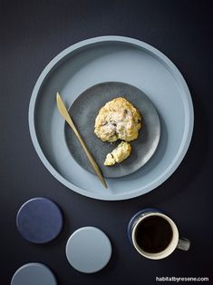 a plate with some food on it next to a cup of coffee and saucer