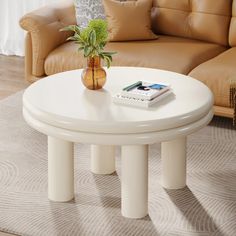 a white coffee table with a potted plant on it in front of a couch