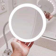 a person holding a mirror in their hand with the light on it's side