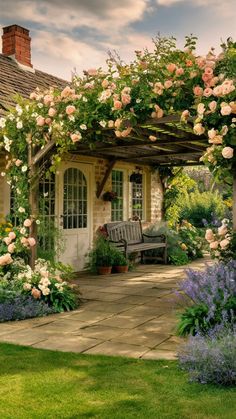 a garden with flowers and a bench in front of a house that has a covered porch