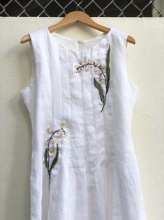 ❤ The white hand embroidered linen dress is very soft, skin friendly, breezy and comfortable.  ❤ Item description: - A lovely dress with embroidered Lily of the valley flowers motifs. - Material: linen, embroidery threads. - Environmentally friendly. - This dress is very useful, go with any outfit, that can be used to go to school, go out, go shopping.    It is a perfect gift for yourself or your beloved.  ❤ Care instructions:       The best way to wash embroidery cloth is to put it in soapy water (with a mild detergent and cold water at 86 ºF/30oС) for 20 minutes. Try to not wash the item with other clothing that might cause damage, such as zippers, buttons or different colors. You wash it by hand, and if you have dirty patches on your garment, you can gently rub them, it's best not to ru White Bohemian Linen Dress Made Of Ramie, White Bohemian Ramie Linen Dress, Summer Embroidered Linen Dress For Garden Party, Summer Linen Embroidered Dress For Garden Party, Summer Garden Party Embroidered Linen Dress, Fitted Linen Dress With Floral Embroidery For Spring, Fitted Linen Dress With Floral Embroidery, White Bohemian Embroidered Linen Dress, Elegant Summer Linen Dress With Floral Embroidery