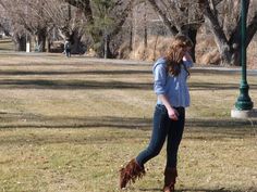 a woman standing on top of a grass covered field