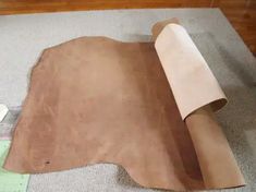 a piece of leather is laying on the floor next to a roll of paper and scissors