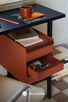 a table with two drawers and a coffee cup on it next to a stack of books