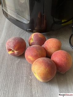 six peaches sitting on top of a counter next to a toaster oven