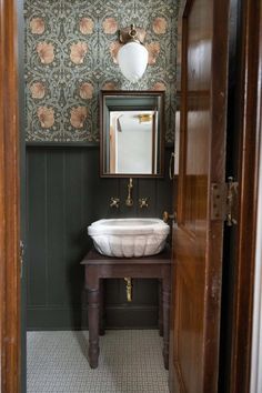 a bathroom sink sitting under a mirror on top of a wooden cabinet next to a doorway