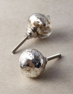 two metal knobs with holes in them on a counter top next to a pair of nails