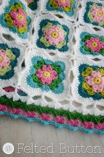 a crocheted blanket with pink and green flowers on it's edges is shown