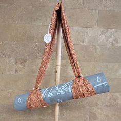 a yoga mat hanging from a wooden pole on the side of a brick wall,