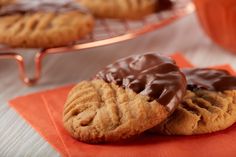 two chocolate covered cookies sitting on top of an orange napkin