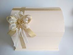 a white box with gold ribbon and a bow