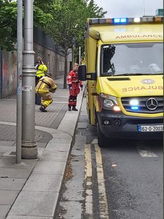 an ambulance is parked on the side of the road with its door open and emergency personnel surrounding it