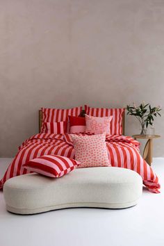 a bed with red and white striped sheets, pillows and blankets on top of it