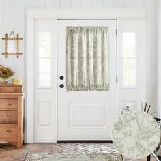 a white door with curtains and a chair in front of it on a rug next to a dresser