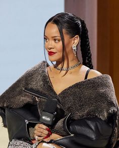 a woman sitting in a chair holding a microphone and wearing a fur stole over her shoulders