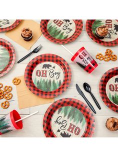 a table topped with red and black plates covered in moose themed paper napkins next to cupcakes