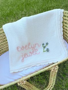 a white crocheted blanket sitting on top of a wicker basket next to a pillow