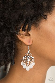 a close up of a woman's face wearing earrings with pearls on the bottom