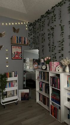 a room filled with lots of books on top of a hard wood floor next to a white book shelf