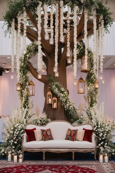 a white couch sitting under a tree with lots of flowers on it's branches