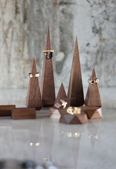 three small wooden trees with gold rings on them